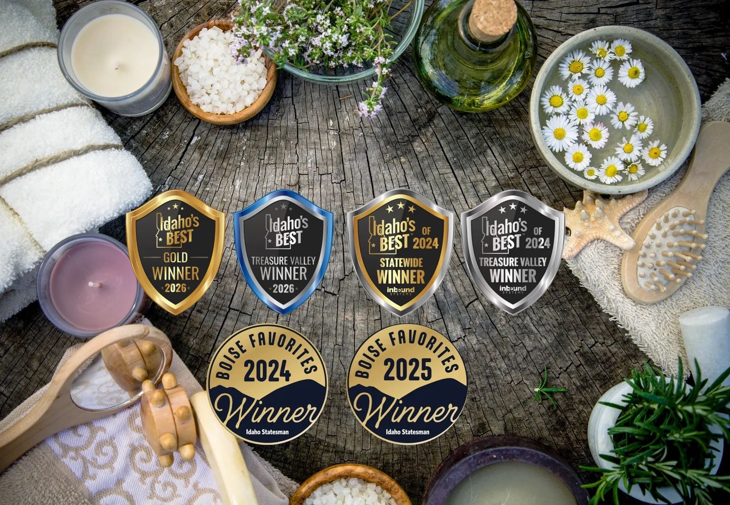 A rustic spa setup with candles, towels, flowers, and award badges on a wooden surface.
