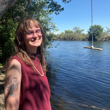 Person smiling by a lake with a rope swing in the background.