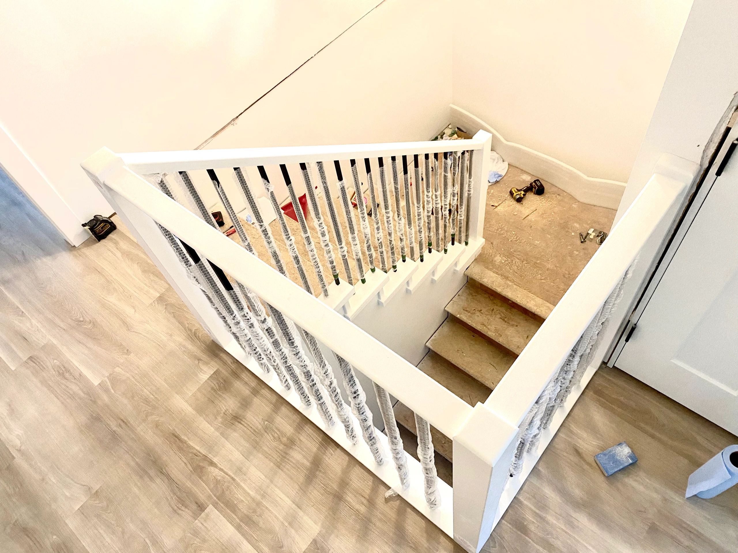 New staircase installation with wrapped spindles and unfinished steps.