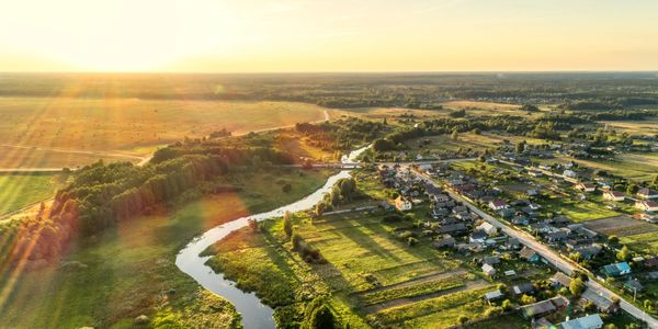 Sunset over a river winding through a village and fields.