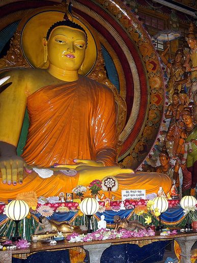 Large golden Buddha statue with intricate decorations and offerings.