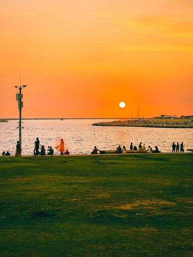 People enjoying a sunset by the waterfront with a vibrant orange sky.
