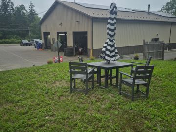 Outdoor seating with a table, chairs, and a striped umbrella on grassy lawn.