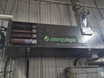 Waste oil heating system unit mounted on a wall inside an industrial building.