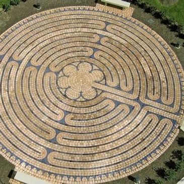A circular brick labyrinth with a flower pattern at the center and benches around it.