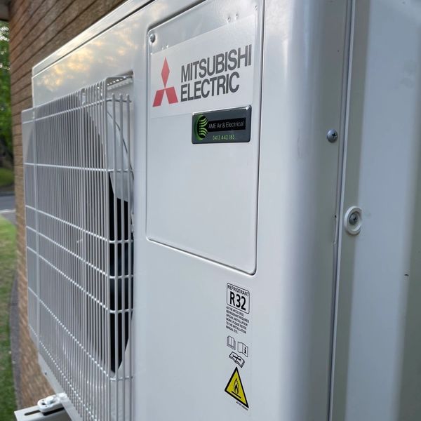Outdoor Mitsubishi Electric air conditioning unit installed beside a brick wall.