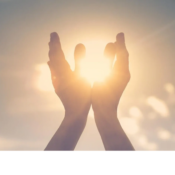 Hands gently cupping the bright sun against a soft sky.