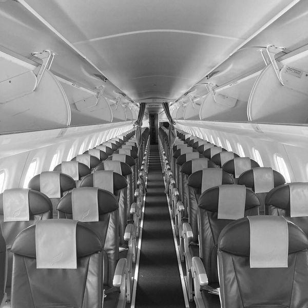 Empty airplane cabin with neat rows of seats in black and white.