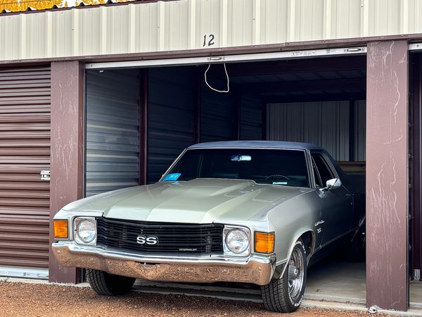 Classic silver Chevrolet  El Camino SS car partly inside a storage unit numbered 12.