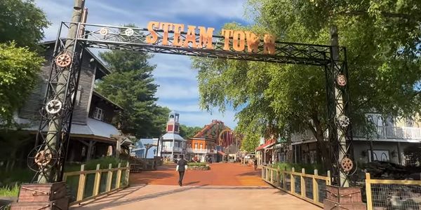 Entrance gate to Steam Town amusement park with colorful buildings and rides.