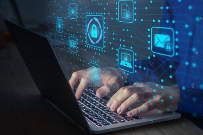 Person typing on laptop with digital security icons.