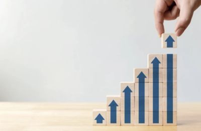 Hand placing the last block on an ascending arrow graph made of wooden blocks.