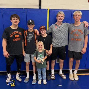 Group of six smiling kids in a gymnasium.
