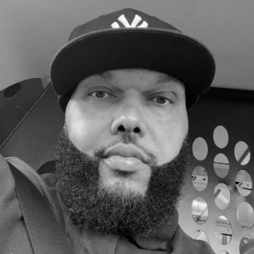 A bearded man wearing a cap.