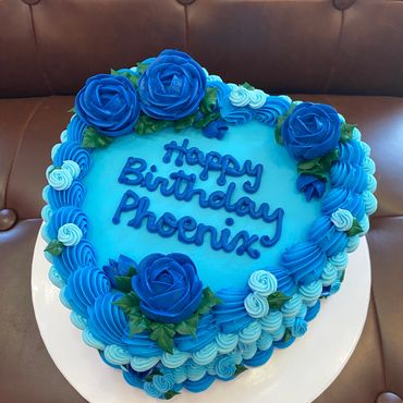 Heart-shaped blue birthday cake with blue roses.