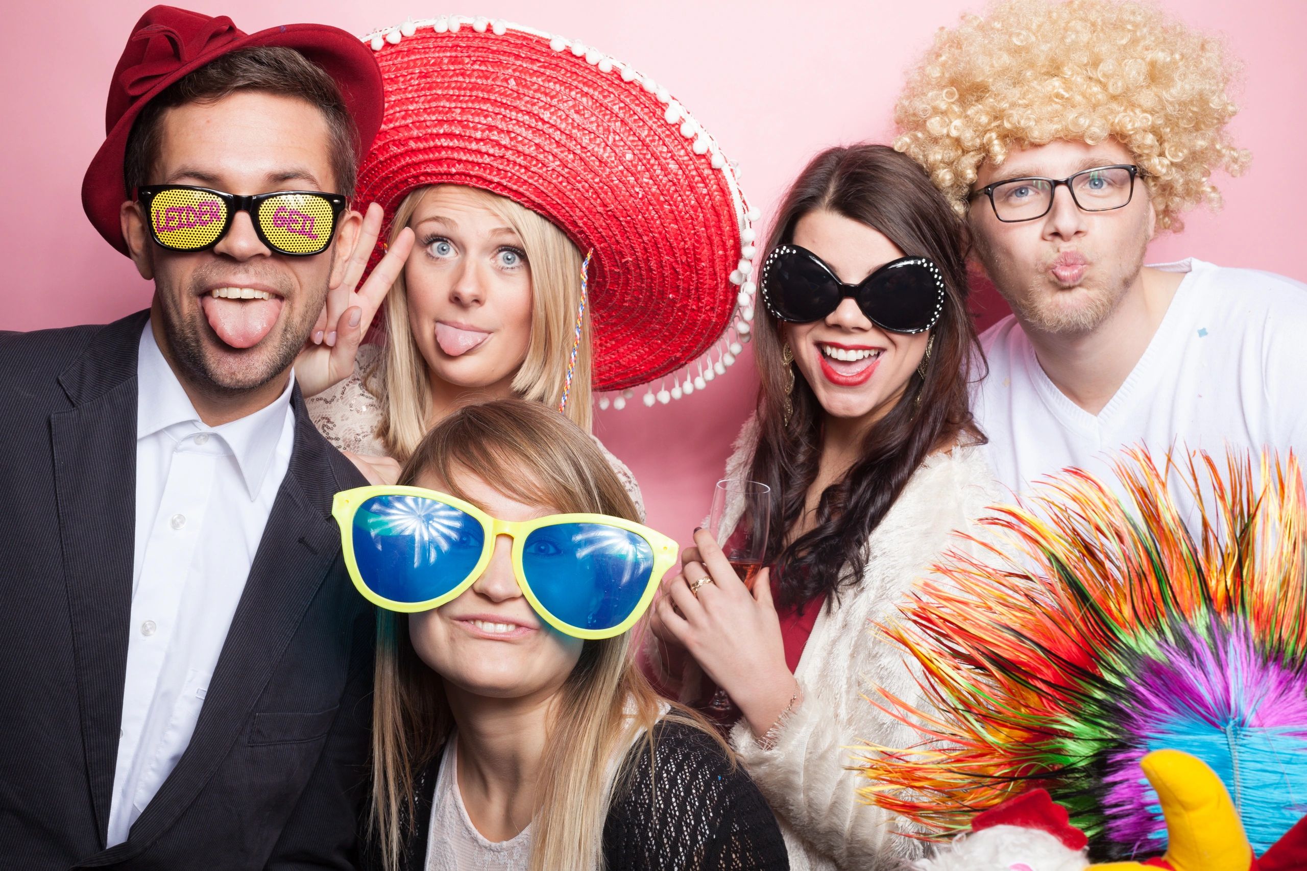 Five friends dressed in playful costumes and oversized sunglasses having fun.