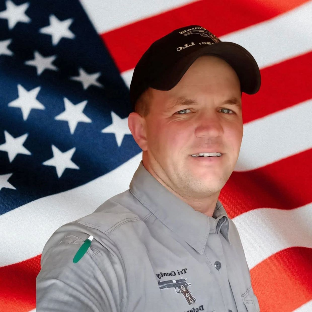 Man in uniform with a cap standing in front of an American flag.