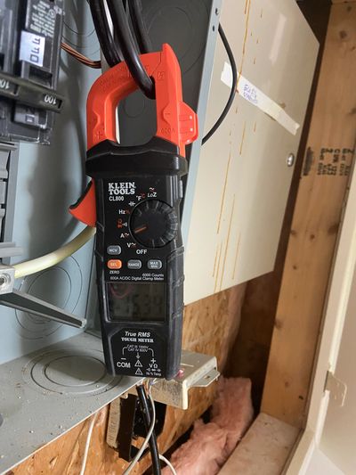 Licensed electrician performing electrical troubleshooting with a clamp meter in a residential elect