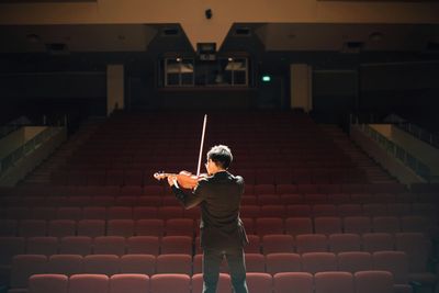 A violinist practices alone on an empty concert hall stage.