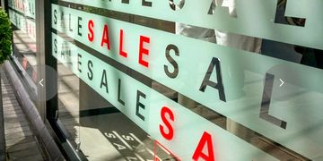 Store window with multiple 'SALE' signs in red and black letters.