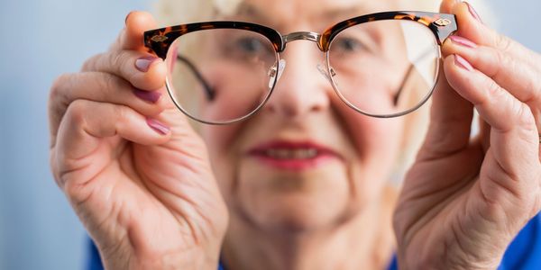 A senior lady looking through a pair of glasses from a distance