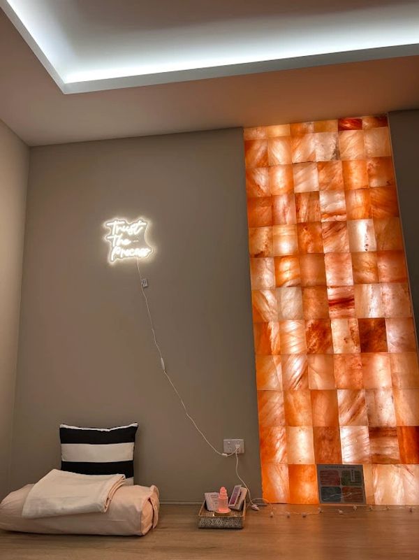 Minimalist room with illuminated wall sign and textured orange panel.
