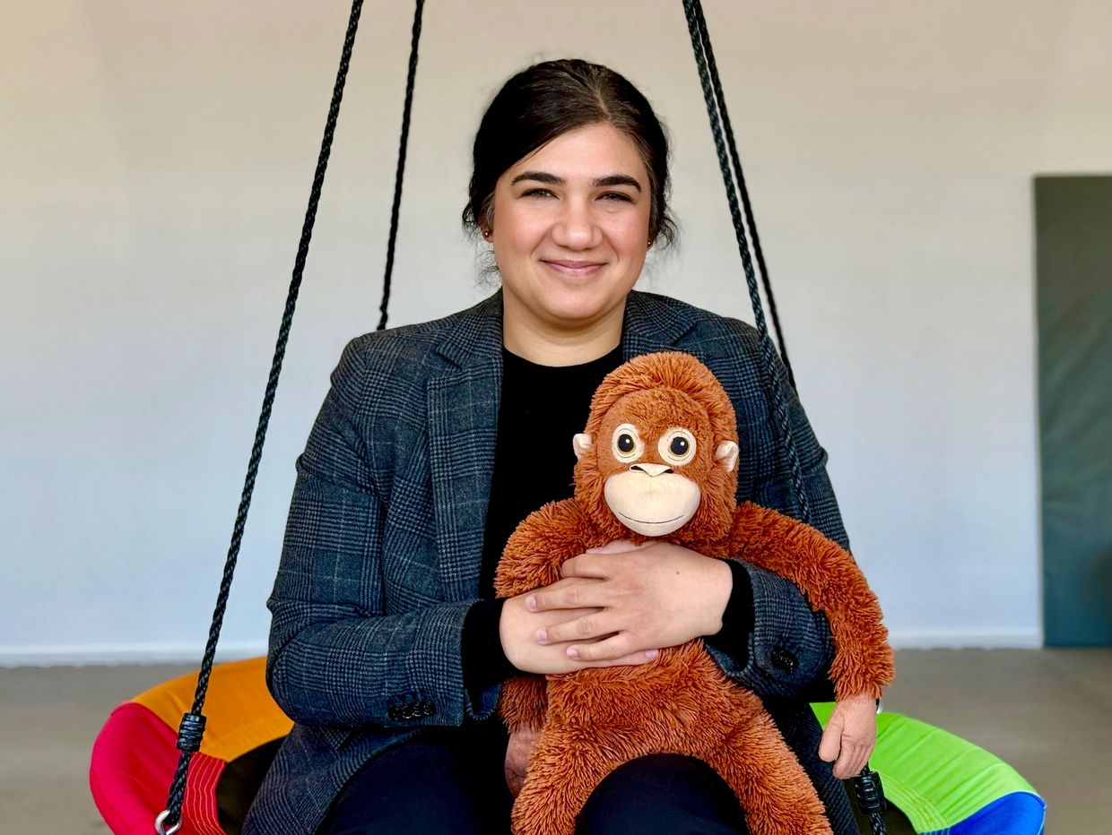 Woman sitting on a swing holding a stuffed monkey.