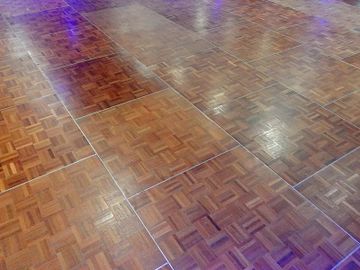 Shiny wooden parquet flooring with a checkered pattern.