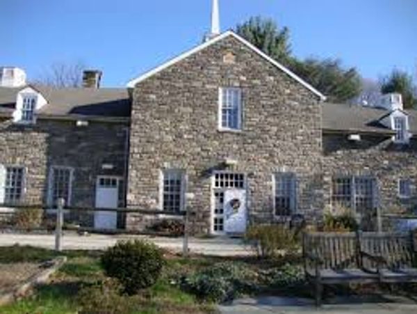 Historic stone building with white doors and windows under a clear blue sky.