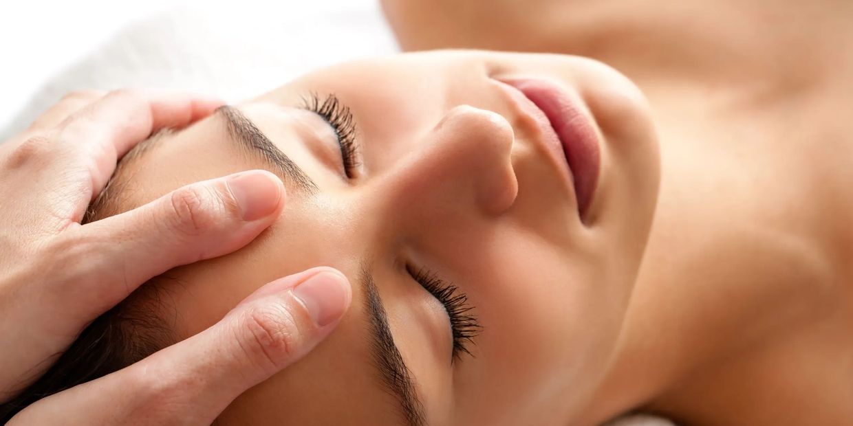 Person receiving a relaxing forehead massage with closed eyes.