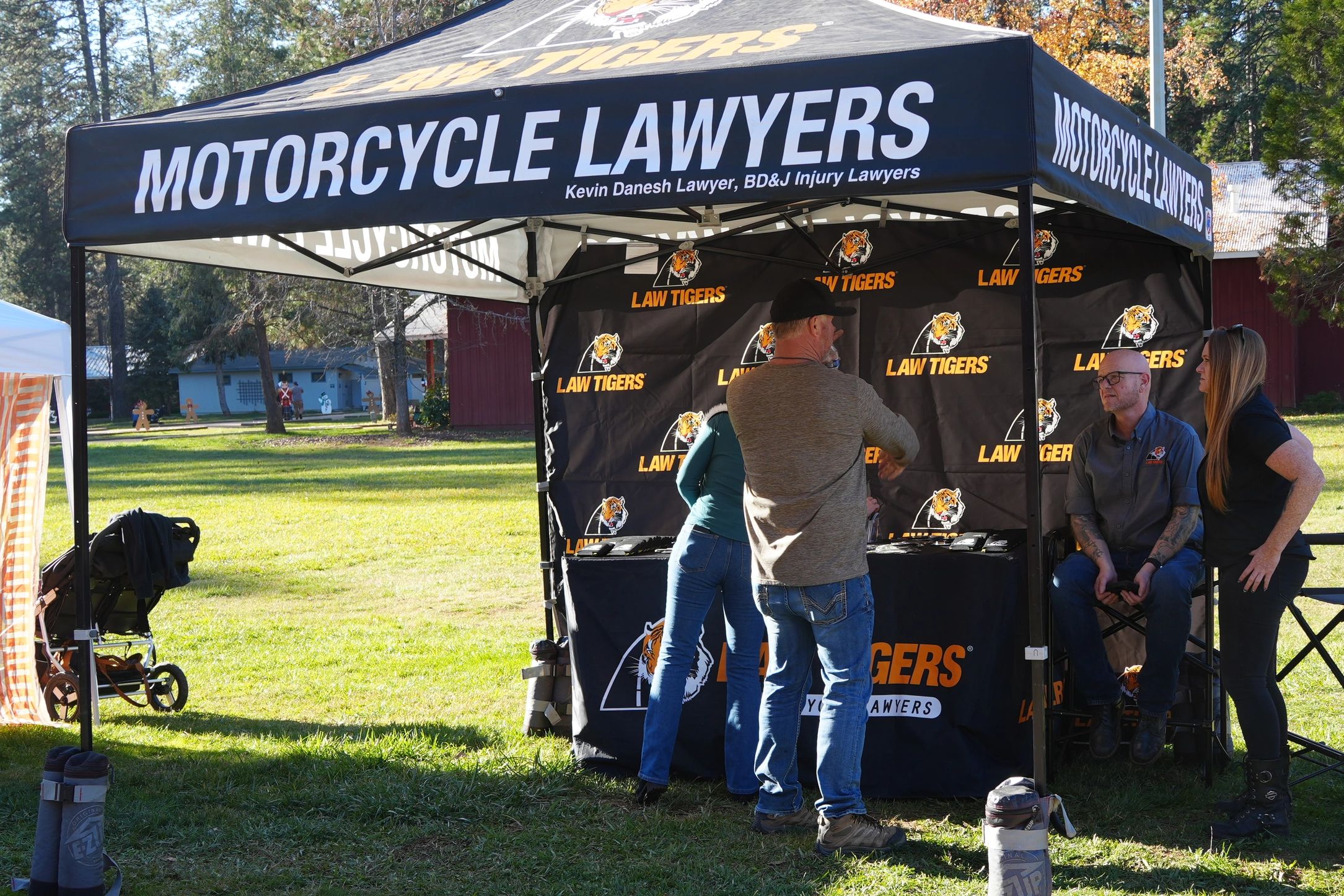 People gather at a Law Tigers motorcycle lawyers tent outdoors.