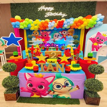 Colorful Pinkfong birthday party setup with balloons and decorations.