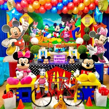Colorful Mickey Mouse themed birthday party setup with balloons and plush toys.
