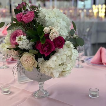 Elegant floral centerpiece with white and pink roses on a pink tablecloth.