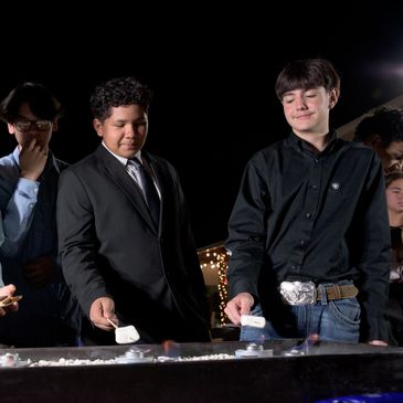 Two boys roasting marshmallows over an outdoor fire pit at night.