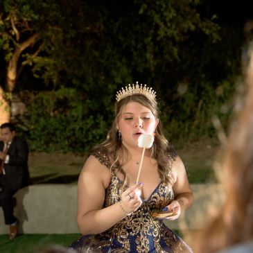 Young woman in elegant dress and crown blowing on a marshmallow.