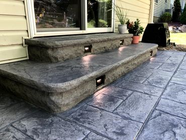Decorative stamped and colored concrete patio and steps with custom lighting added to concrete stepsn