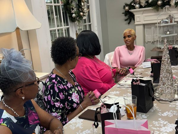 Four women engaged in conversation at a decorated table with gift bags.