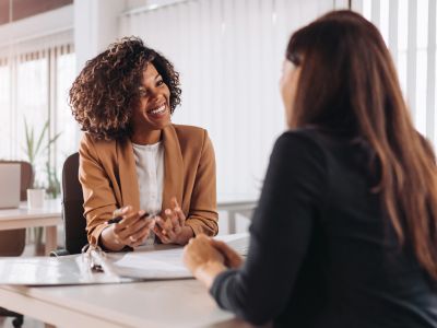 Two women engaged in a friendly conversation at work.