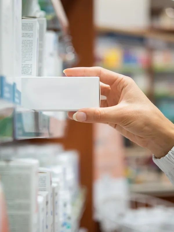 Hand picking a white box from a store shelf.