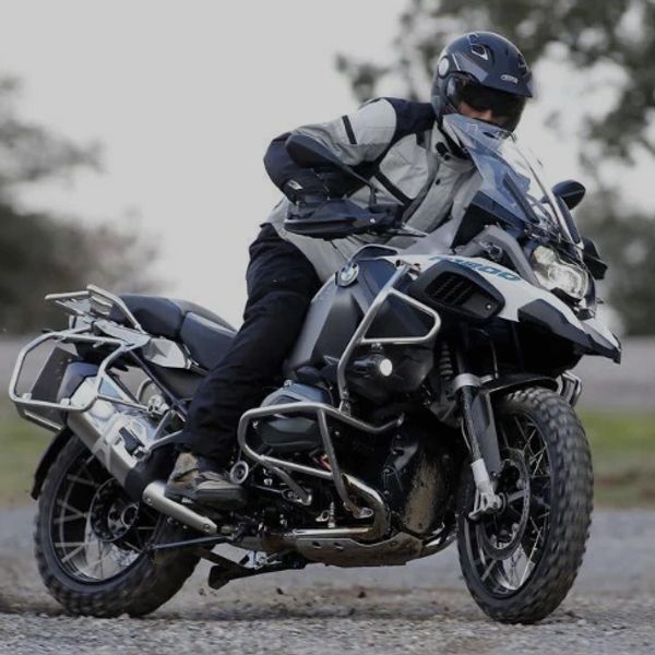 A person riding a BMW adventure motorcycle on a gravel path.