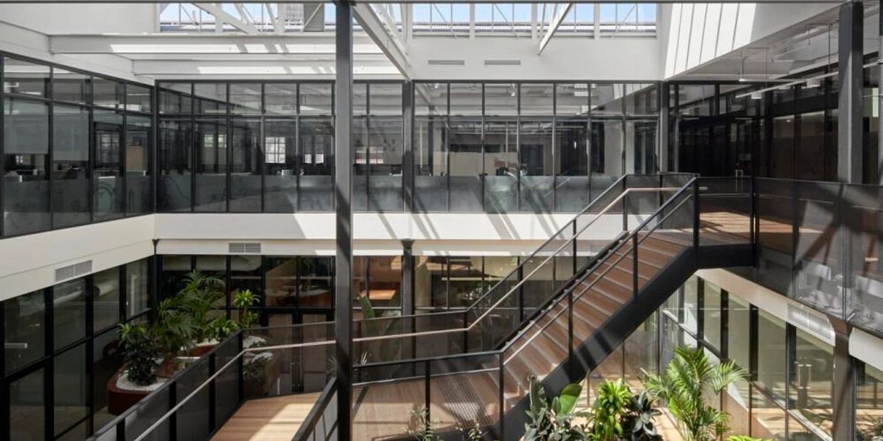 Bright modern office atrium with glass walls and indoor plants.