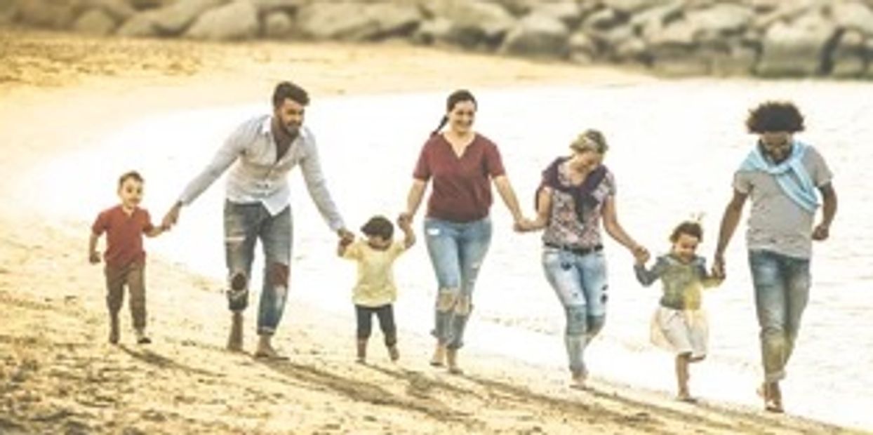 Family of six walking hand in hand on the beach at sunset.