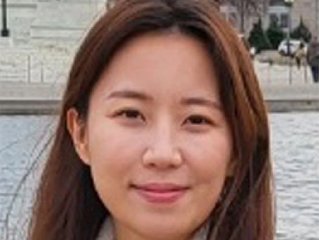 Portrait of a smiling woman with brown hair outdoors.