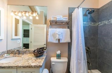Clean and elegant bathroom featuring a granite countertop, modern lighting, and a full-sized tub.