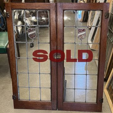 Pair of Tudor style antique cabinet doors circa 1920s with red stained glass shield