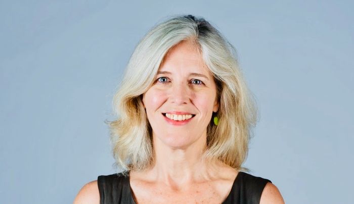 headshot of a woman with green earring