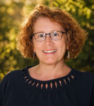 Smiling woman with glasses outdoors.