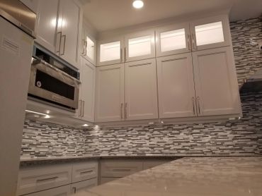 Modern white kitchen with mosaic tile backsplash.