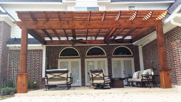 Wooden pergola with outdoor seating in a backyard.
